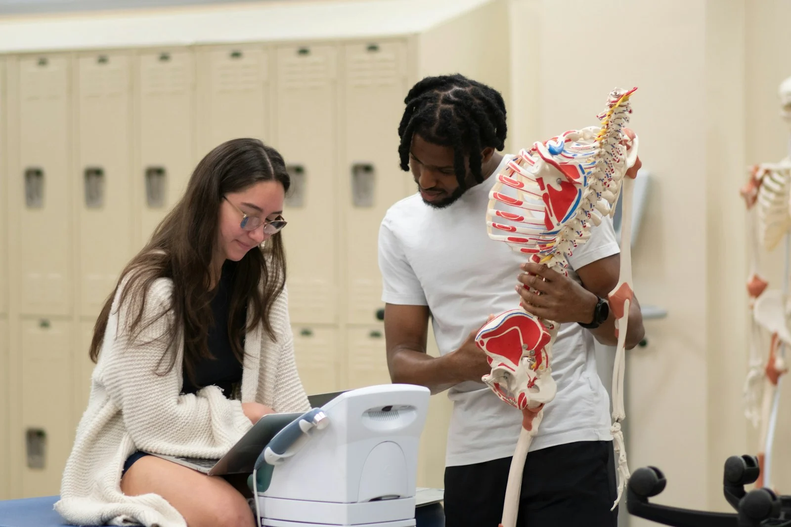A man and a woman looking at a model of a skeleton